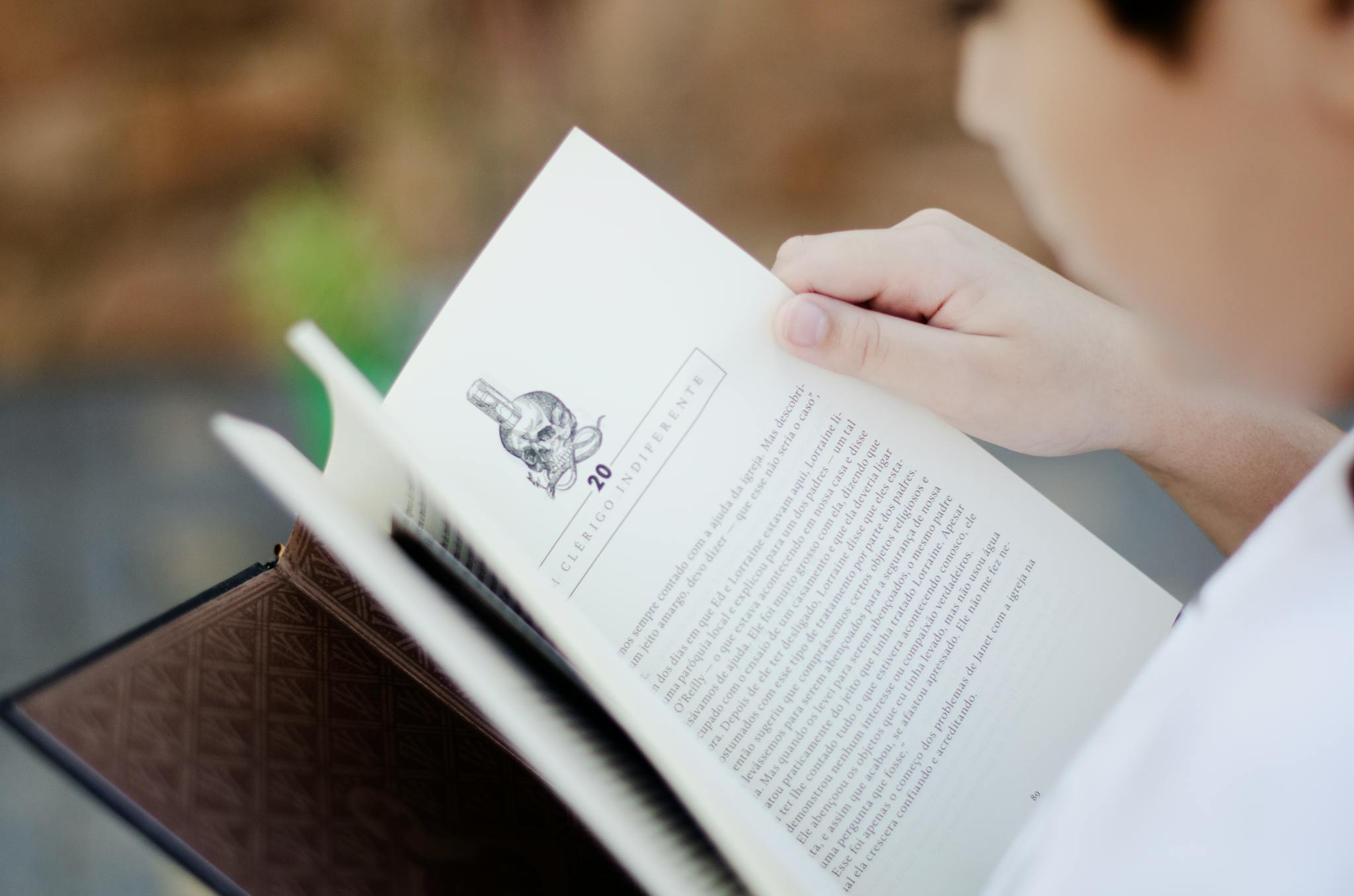 Close-up of a man reading a book outdoors, focusing on learning and relaxation.