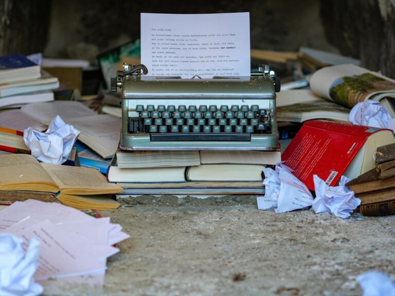 A vintage typewriter surrounded by open books and crumpled papers, symbolizing creative chaos.